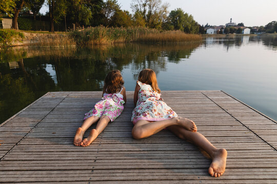 Little sisters lying together look at the lake
