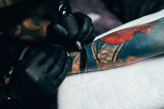 Tattooist making tattoo on hand