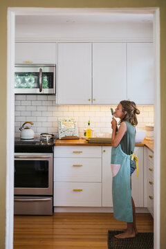 Young girl baking by herself in the kitchen and taste testing th