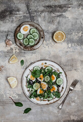 salad with fresh cucumbers, herbs, soft boiled eggs and lemon dressing on ceramic plate, seasonal healthy eating concept, copy space