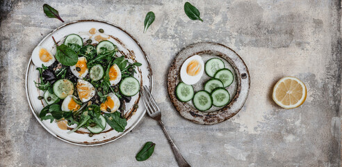 salad with fresh cucumbers, herbs, soft boiled eggs and lemon dressing on ceramic plate, seasonal healthy eating concept, copy space