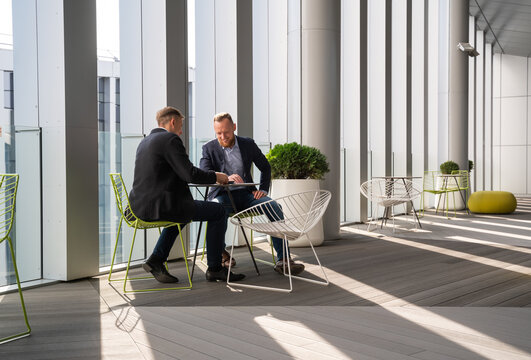 Businessmen Talking At Luminous Office Terrace