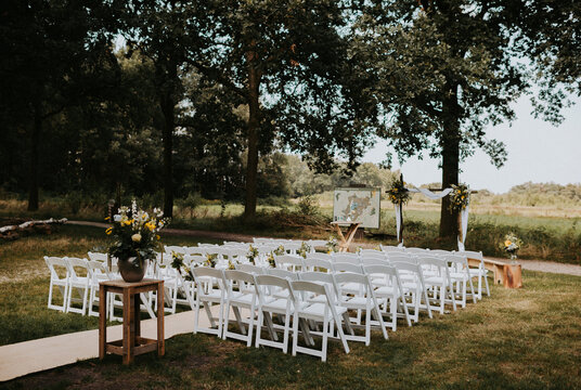 outdoor wedding ceremony set up with white chairs and bohemian flowers