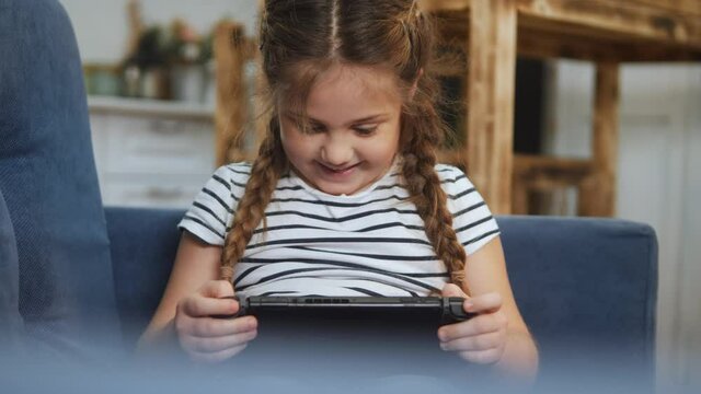little girl playing handheld a game console. kids dream stay home computer addiction. girl playing tablet online games. addiction to online games addict kid. child play game fun console dream