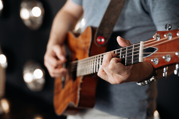 Crop man playing guitar in studio