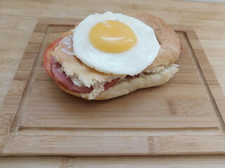 Sandwich with cheese bacon and fried egg on wooden background