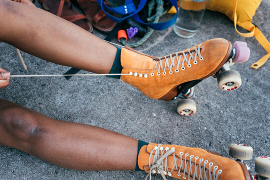 Unrecognizable African American woman tying shoe laces on her or