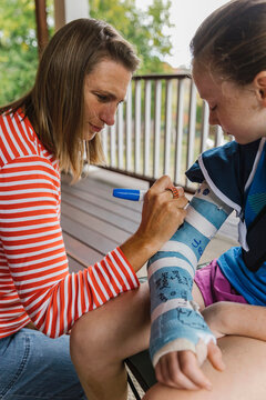 Mother using pen to sign Cast on Broken Arm