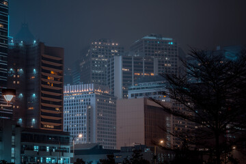 Naklejka premium Modern office buildings in Hong Kong at foggy night