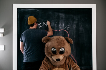 Man in a bear costume sitting in front of a chalkboard