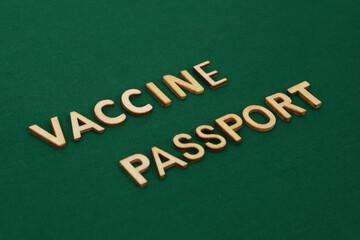 Fototapeta premium COVID vaccine passport wooden alphabet letters on a green fabric. Green Passport.