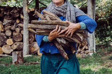anonymous woman carrying wood for burning
