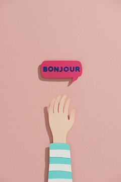 Raised arms near hello word speech bubbles in French make by paper.