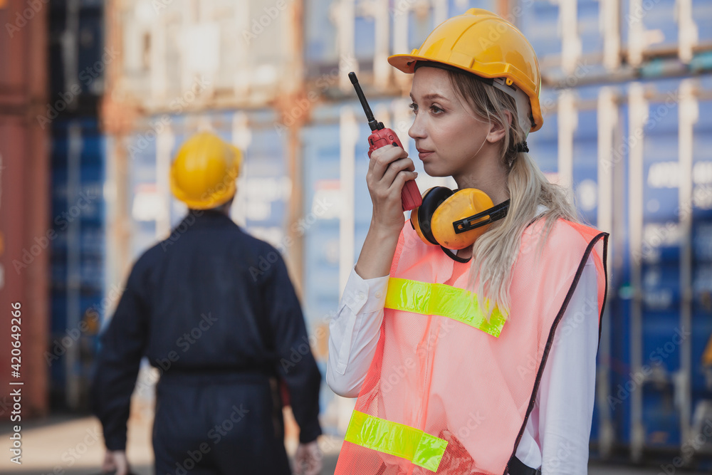 Poster female worker using handheld radio receiver for communication. working engineer in the construction 