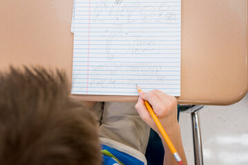 Boy's hands taking notes in a class