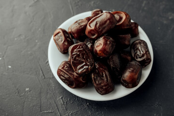 dried dates on farvor plate on dark background top view. traditional oriental sweets. healthy natural snack. selective focus