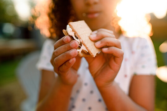 Girl eating s'more in golden sunlight