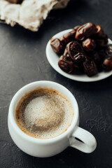 oriental style coffee: freshly brewed drink with foam, dried dates in a vintage plate, honey. dark mood image. food content. vertical, selective focus