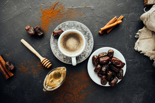 Eid Al-Adha. Freshly Brewed Coffee, Dried Dates, Cinnamon Sticks, Honey, Spilled Coffee And Spices, Burlap Cloth On Dark Background. Colorful Image National Food And Drink. Top View, Selective Focus