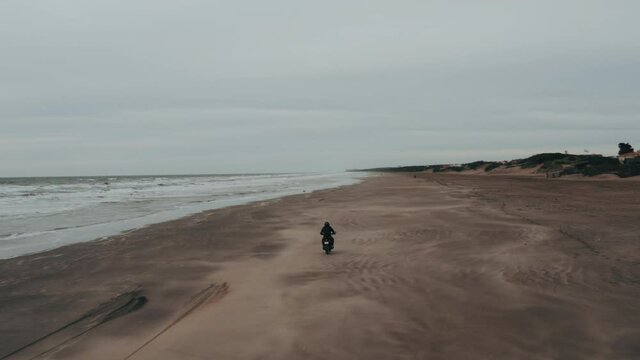 Aerial View of Person Wearing All Black Riding a Motorcycle On The Sand