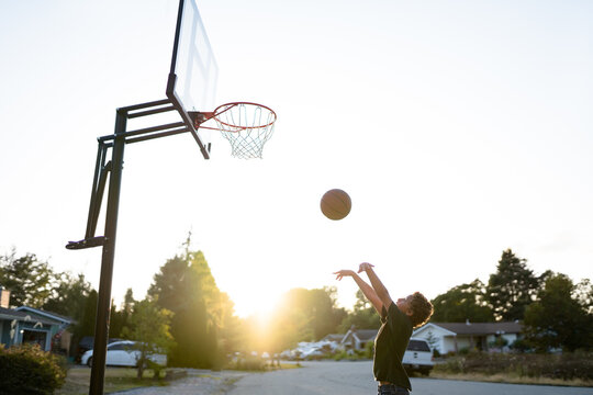 Boy Makes Awkward Basketball Shot In Evening Light