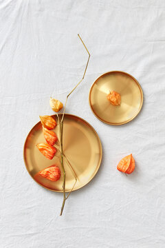 Natural twig of physalis plant on a golden plates.