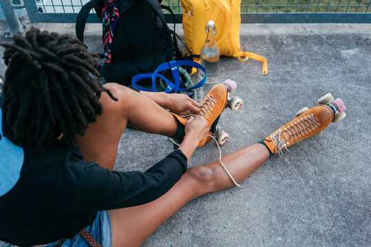 Unrecognisable African American woman tying shoe laces on her roller skate