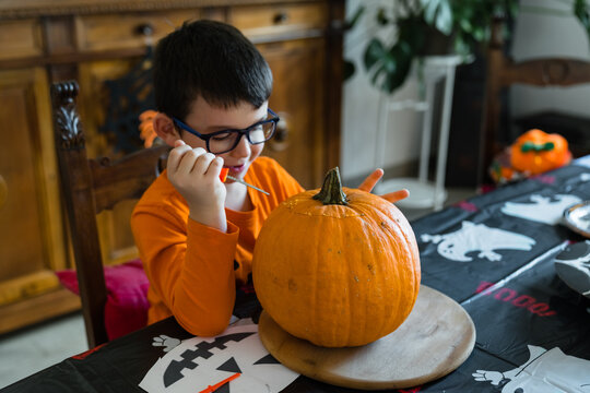 Child cutting jack o lantern from pumpkin