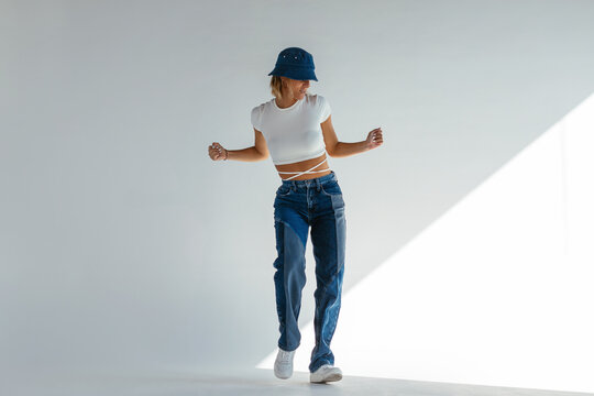 Stylish woman dancing against gray wall