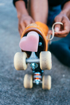 Close up of a pink heart-shaped brake on an orange roller skate.