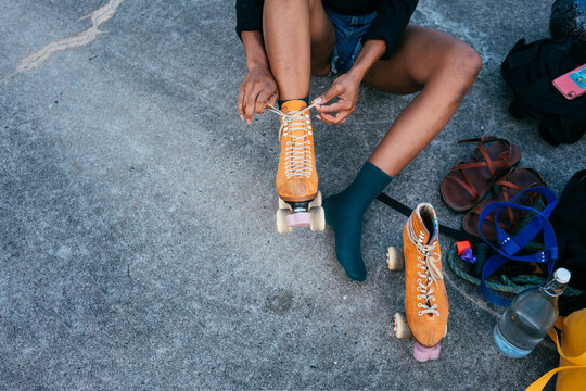 Unrecognizable African American woman tying shoe laces on her roller skate