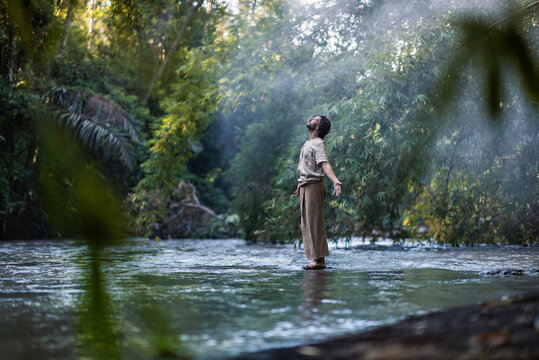 Man practicing Tai Chi on riverside in forested area, on misty morning in Bali