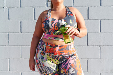 Full-figured woman drinking water after a workout