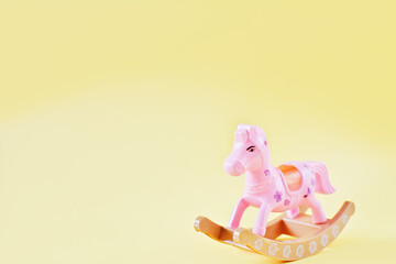 rocking horse toy for kids. small pink horse on yellow background. gift for children of preschool age. emotional intelligence development. copy space for text