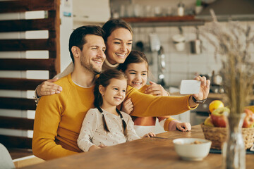 Happy family having fun while taking selfie with cell phone at home.