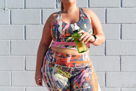 Full-figured woman drinking water after a workout