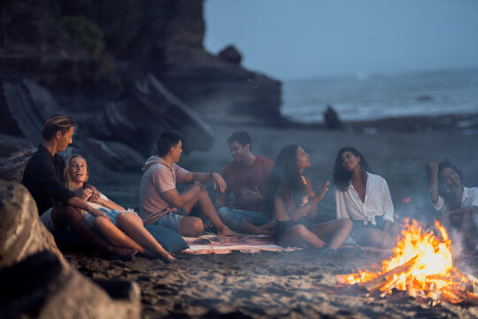 Group of friends gathered around summer fire - laughing and enjoining each others company