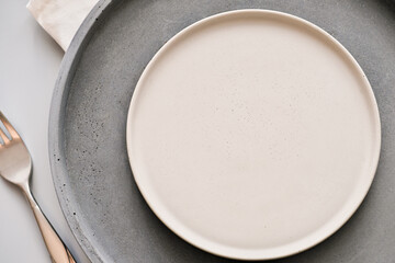 empty grey plates on a table with fork and knife. spring menu concept. trendy nordic minimal style tableware. restaurant menu mock up, scandinavian tableware design, top view