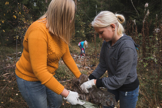Woman and children collect plastic litter in the forest