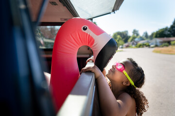 Girl looks at flamingo floatie in back of truck