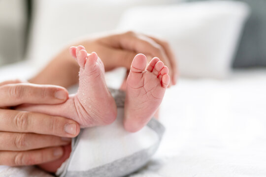 Mother holding newborn baby feet