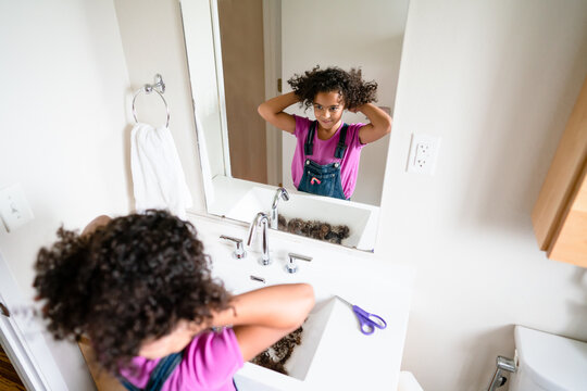 Curly haired girl flips her curly hair in the mirror