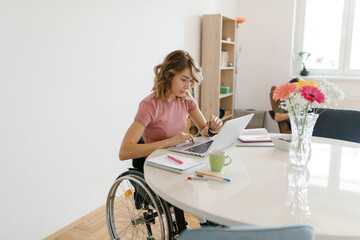 Young woman in a wheelchair working from home on her laptop
