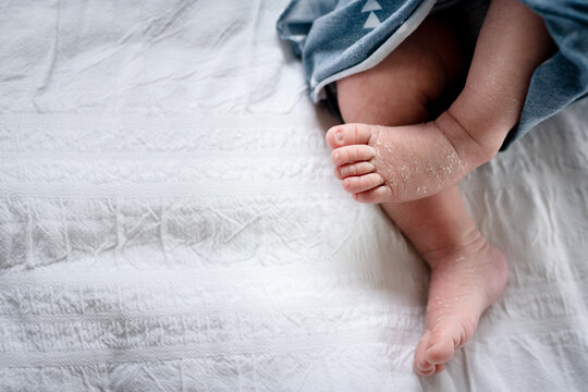 Newborn infant feet on white bed