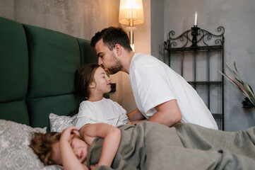 Father kissing sleeping daughters in evening