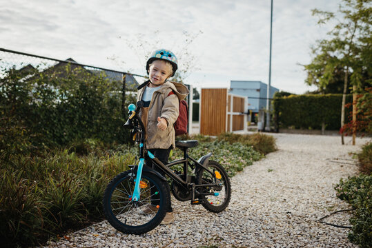 Toddler boy with his black bike, ready to drive to school