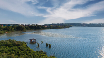 Aerial view of forest and blue lake. Wooden pier with fishing boats.