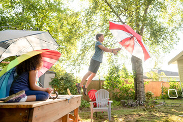 Boy leaping off deck with umbrella