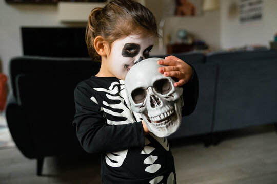 Adorable little skeleton kissing skull