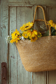 Straw purse with sunflowers on old door